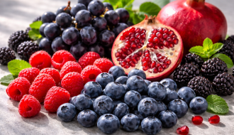Assortiment de fruits riches en polyphénols – myrtilles, framboises, grenade et raisin noir éclairés en lumière naturelle